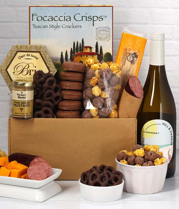 A gift set featuring a bottle of Hill & Harbor Chardonnay, focaccia crisps, 2 cheeses, mustard, summer sausage, caramel popcorn, chocolate pretzels, and 6 chocolate-covered Oreos for a sweet and savory gourmet experience.