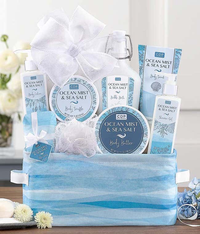 Ocean Mist &amp; Sea Salt gift set displayed in a blue and white patterned basket, featuring body lotion, body butter, shower gel, bath salts, a body souffl&eacute;, and a mesh sponge