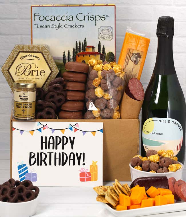 A gift set featuring a bottle of California Sparkling Wine, focaccia crisps, two cheeses, mustard, summer sausage, caramel popcorn, chocolate pretzels, six chocolate-covered Oreos and a Birthday card to complete the gourmet experience.