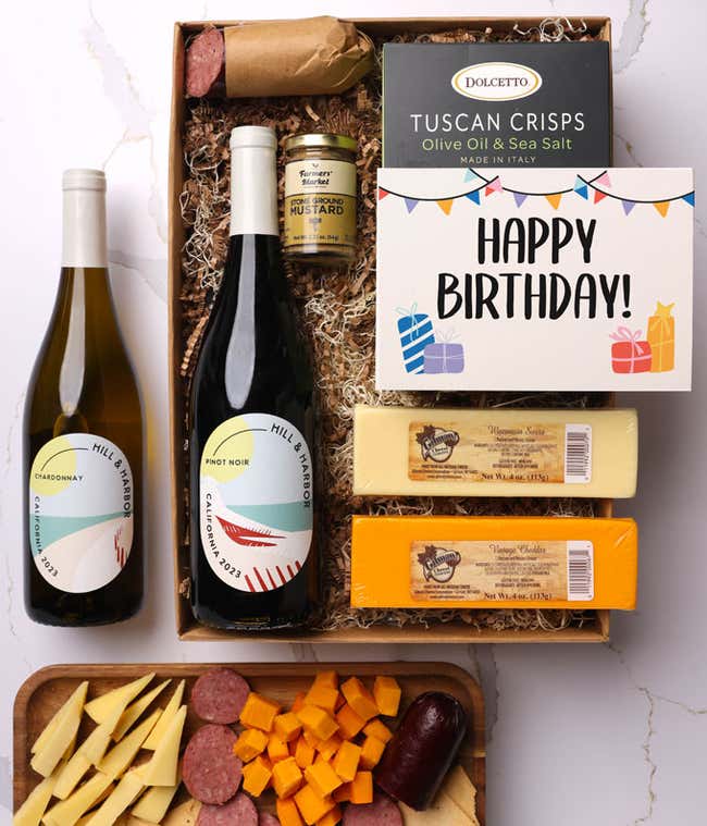 A gift box with two bottles of California wine (Pinot Noir and Chardonnay), two types of cheese, crackers, stone-ground mustard, a summer sausage, and a cheerful birthday card. 